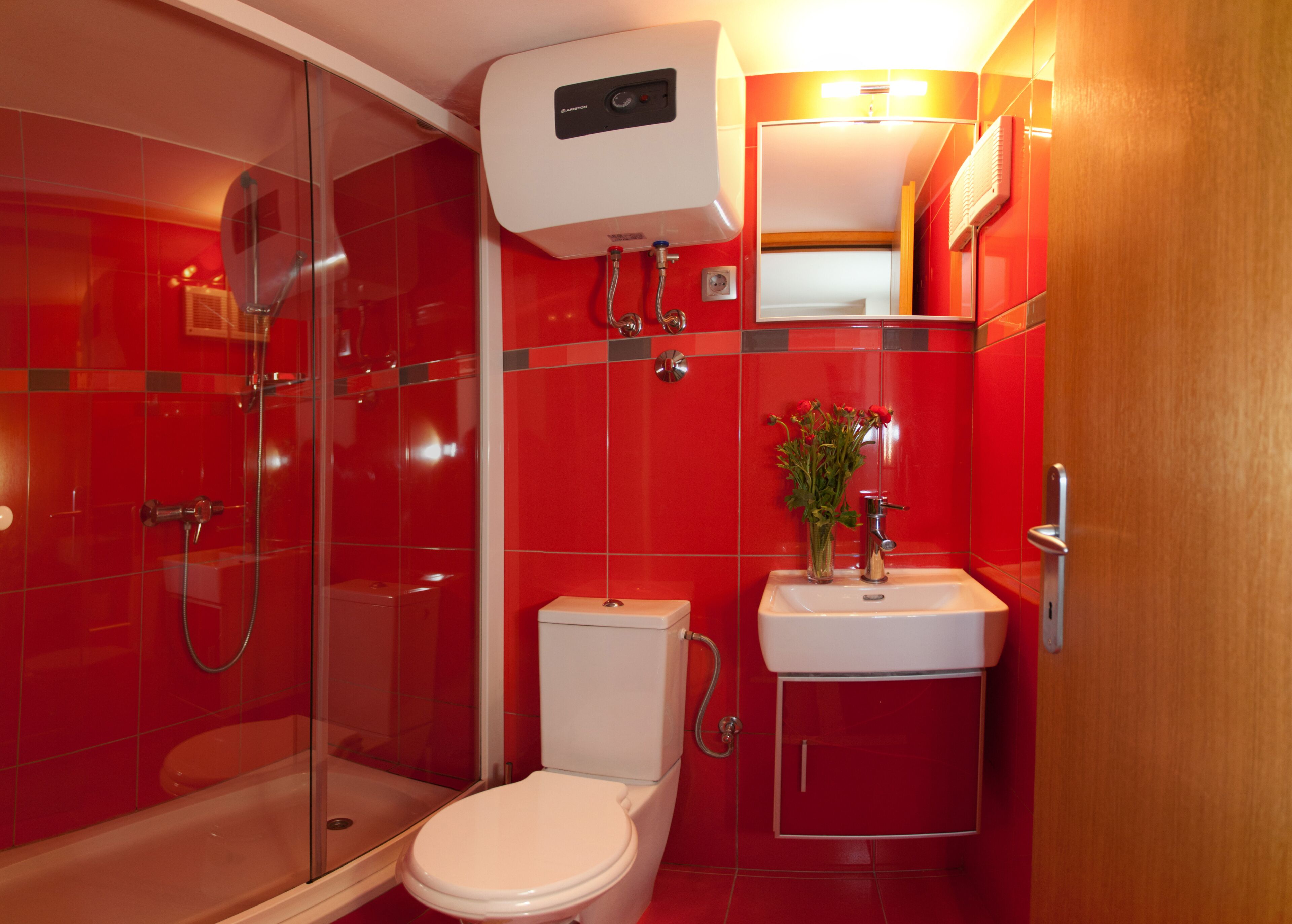 Ein modernes Badezimmer mit Duschkabine aus Glas, Toilette und Waschbecken mit Spiegel darüber.