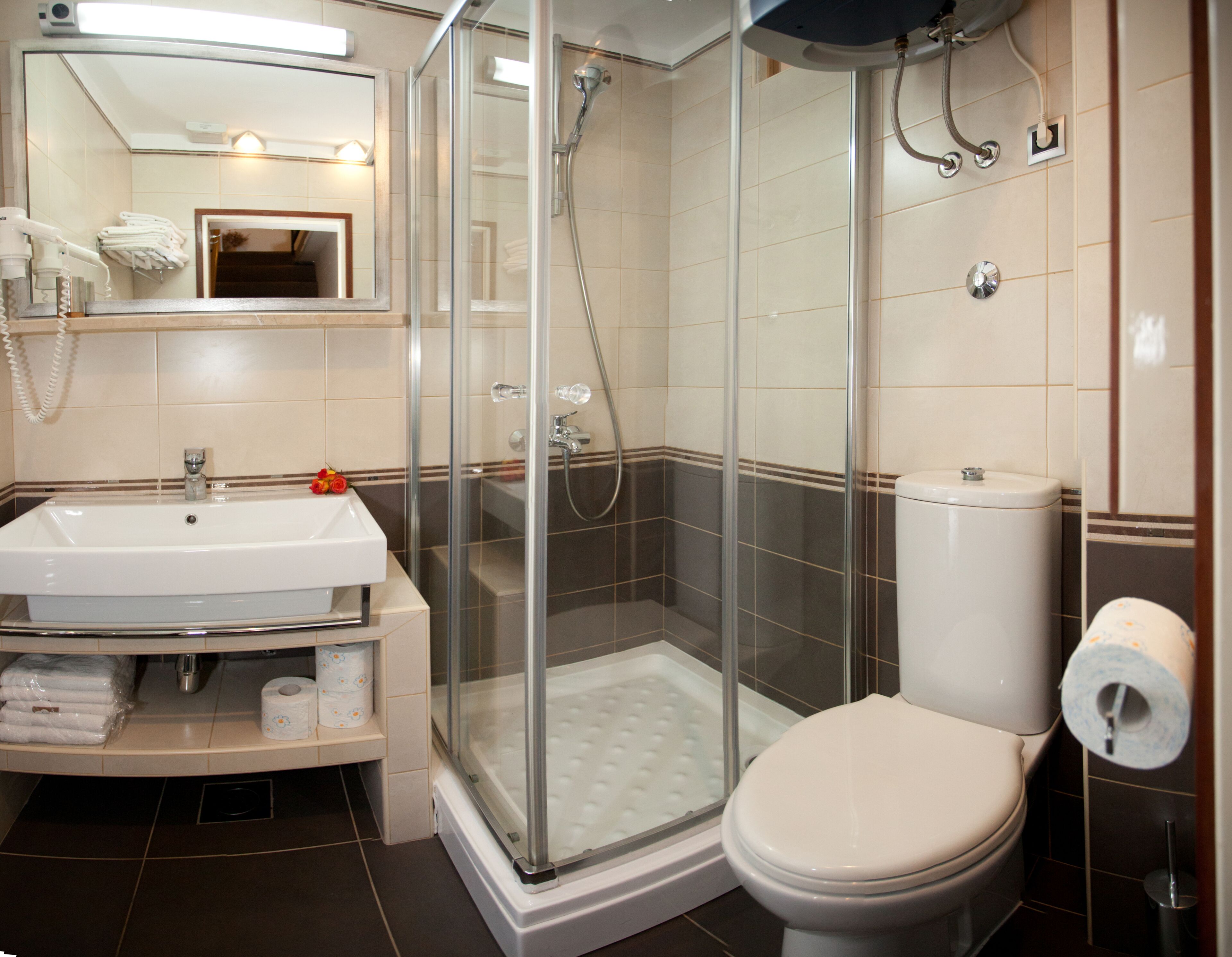 Un baño moderno con ducha de vidrio, lavamanos blanco y retrete.