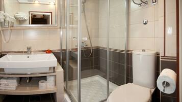 Un baño moderno con ducha de vidrio, lavamanos blanco y retrete.