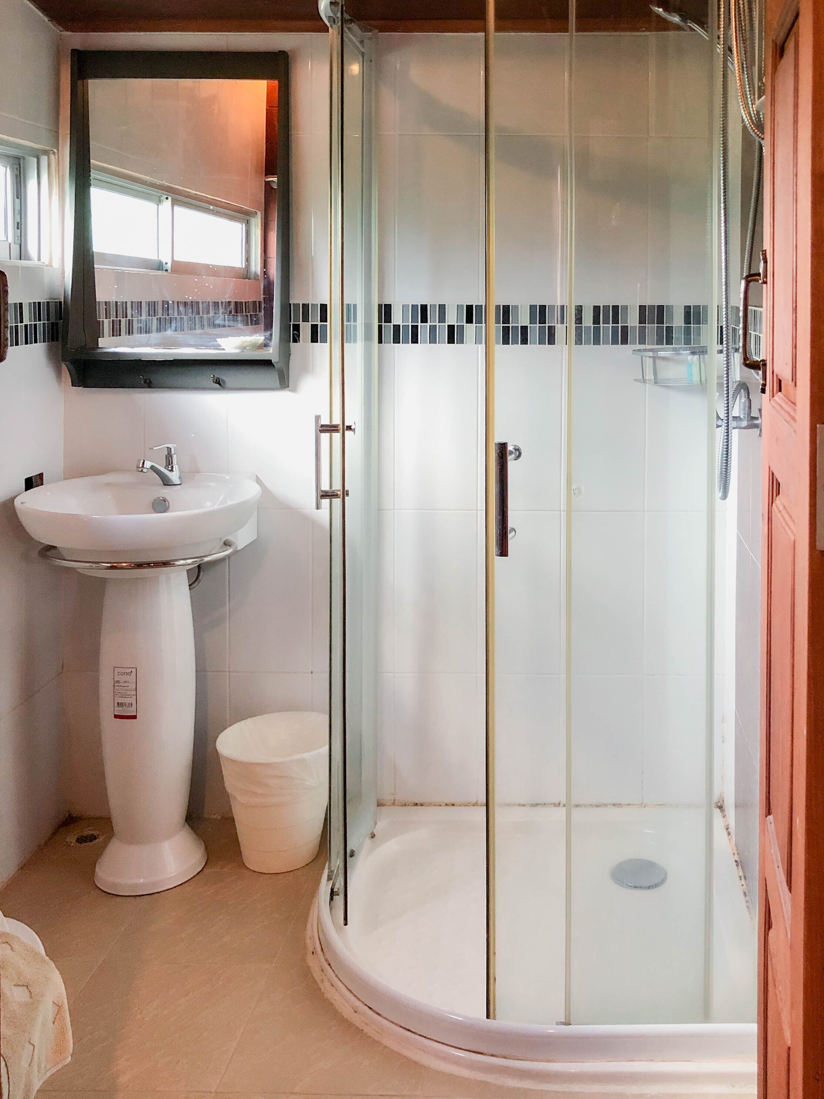 Un bagno con un lavabo su piedistallo, una cabina doccia in vetro e uno specchio sopra il lavabo.