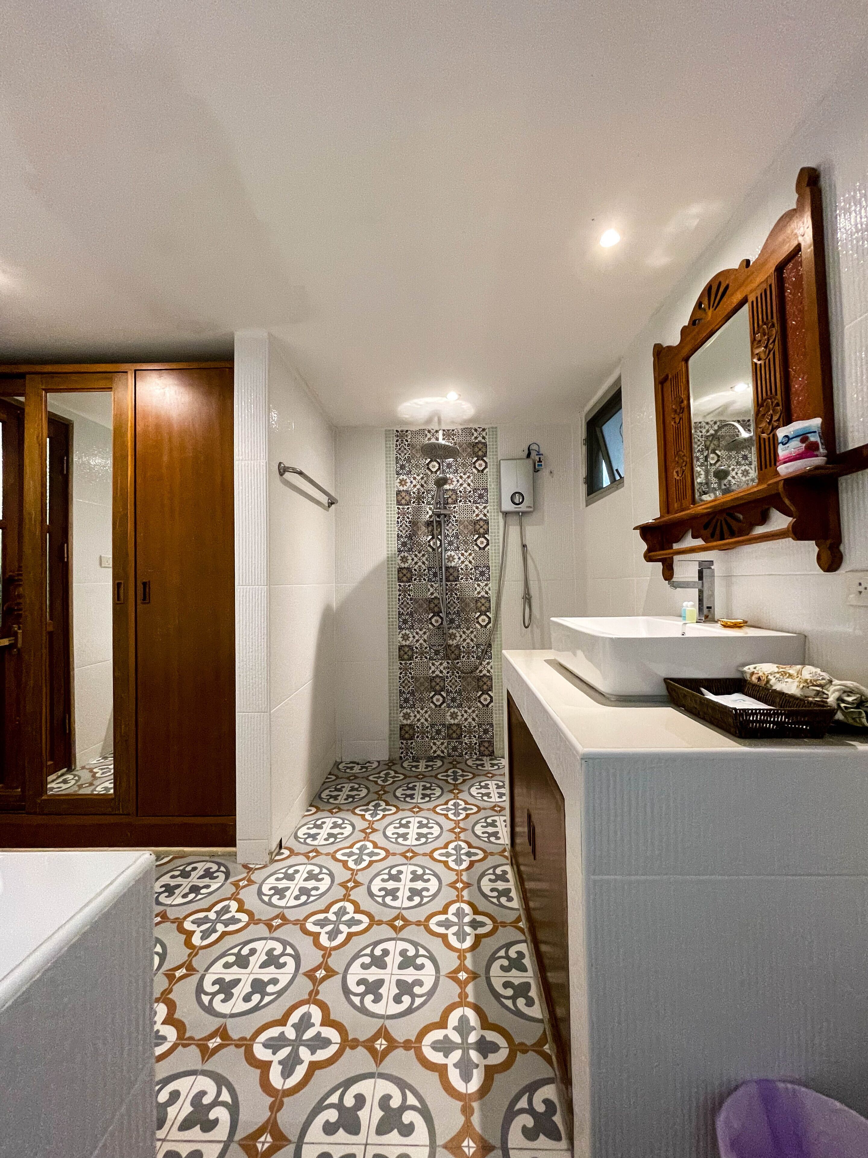 A bathroom with a patterned floor, a bathtub, a sink, and a mirror.