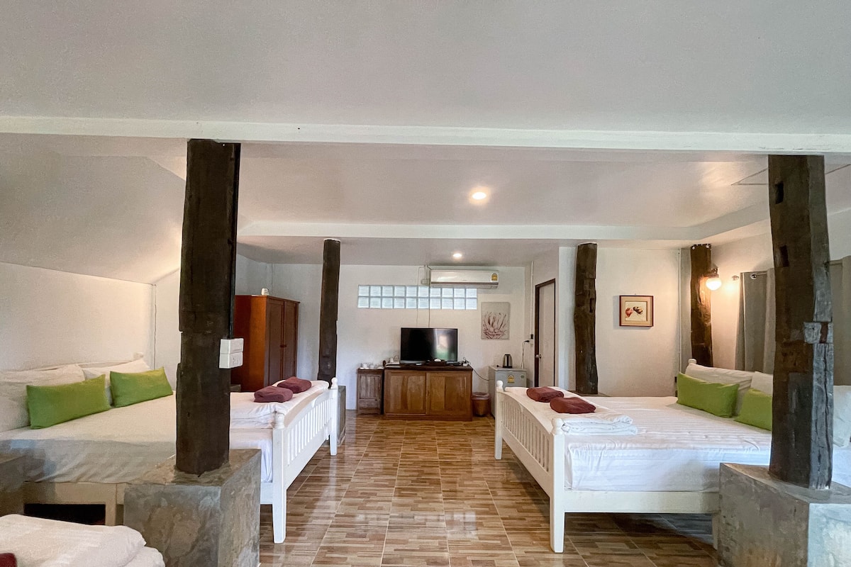 A room with two single beds, a TV, and a wooden cabinet.