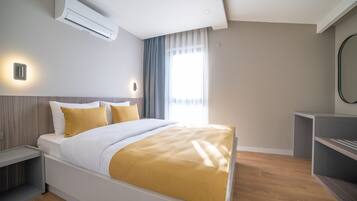 Ein modernes Hotelzimmer mit Bett, Nachttischen, Klimaanlage, Schreibtisch und Spiegel.