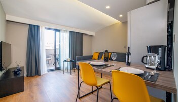 Una habitación de hotel moderna con comedor, sofá y cafetera.