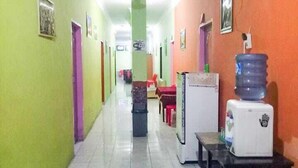 Um corredor com paredes verdes e laranjas, um ventilador de teto e um bebedouro.