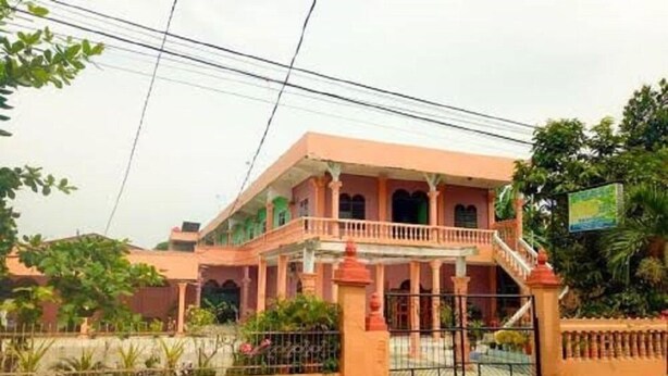 Um edifício de dois andares com varanda, entrada com portão e placa.