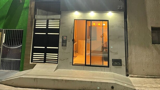 Um edifício moderno com uma placa indicando 'Matzon Apart Hotel'. Apresenta entrada de vidro, portão de metal e rampa que leva à porta.