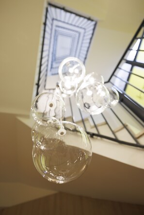 A clear glass bottle with a stopper, a smaller glass object, and a metal rack with a window in the background.