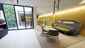 A modern interior with a sofa, chairs, a table, and a glass door leading outside. - Inn Boutique León (León)