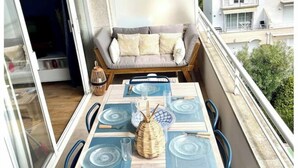Un balcón con una mesa de comedor para cuatro personas, un sofá y vistas a la ciudad.