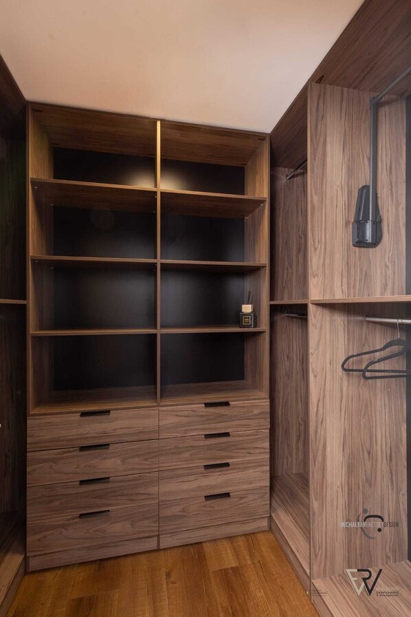 Um closet espaçoso com várias prateleiras e gavetas, uma barra para pendurar roupas e um objeto decorativo em uma das prateleiras.