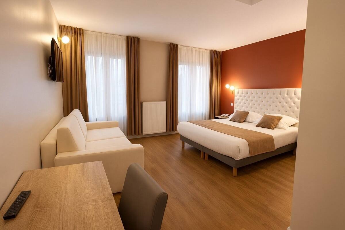 Habitació d'hotel amb llit, sofà, taula i televisió.