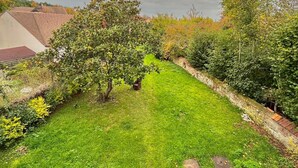 A well-maintained garden with a grassy lawn, a small seating area with chairs and a table, and a variety of trees and shrubs. - Thoiry Etoile Lodge, Sure Hotel Collection by Best Western (Thoiry)