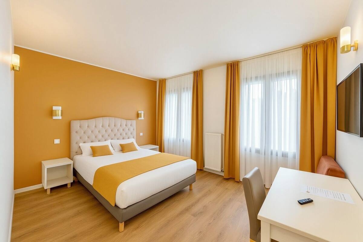 Habitació d'hotel amb llit, taules de nit, escriptori i una cadira.