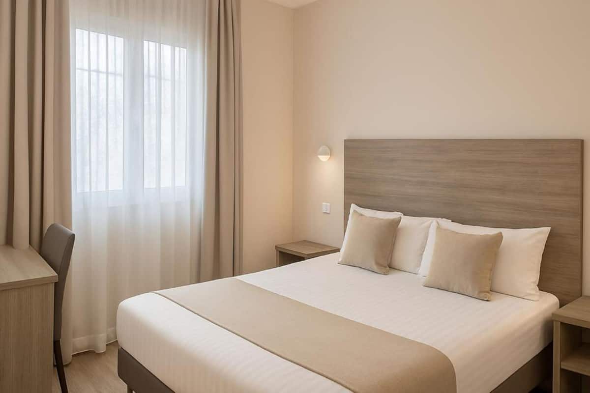Habitació d'hotel amb un llit gran, un escriptori i una cadira.