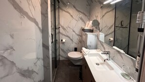 A modern bathroom with a marble wall, a glass shower enclosure, a toilet, and a sink with a mirror. - Thoiry Etoile Lodge, Sure Hotel Collection by Best Western (Thoiry)