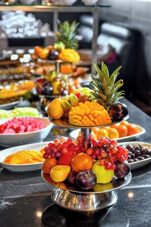 Un bufé con diversas frutas y verduras dispuestas sobre un soporte metálico.