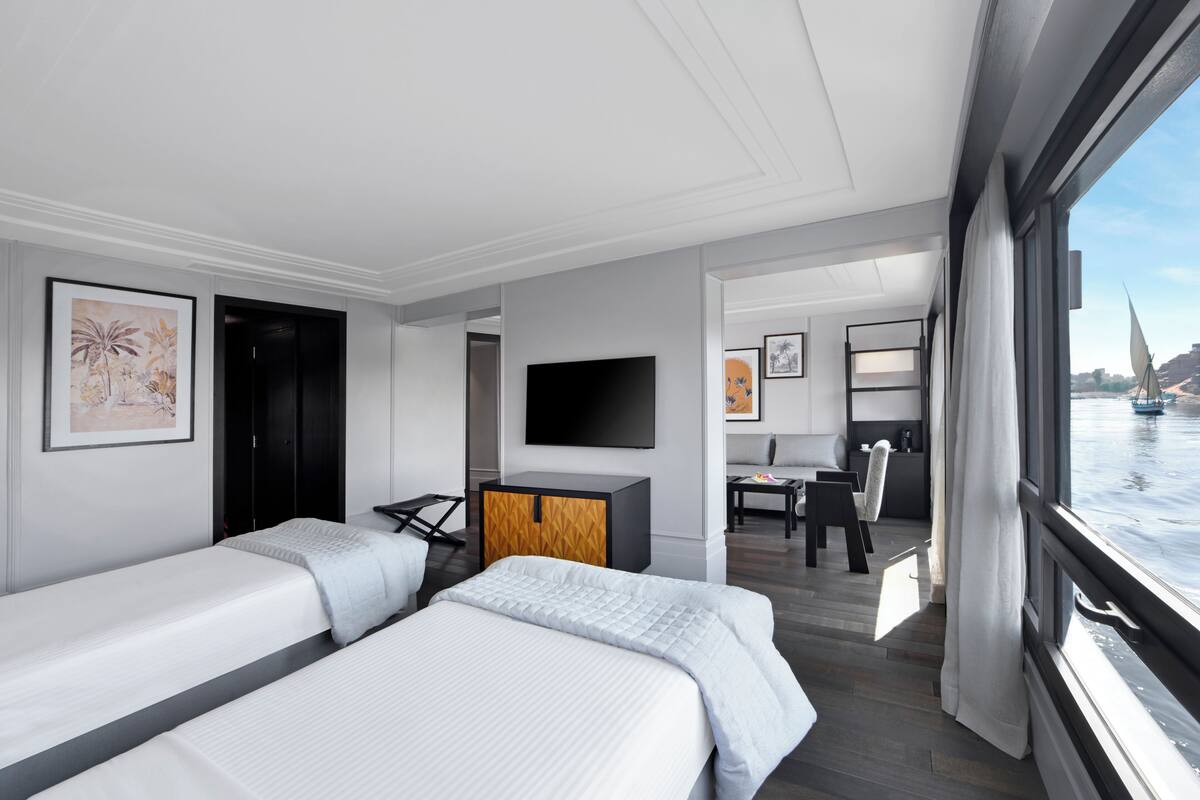 Une chambre d’hôtel moderne avec deux lits, un bureau, une télévision et une vue sur l’eau.
