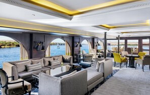 A luxurious interior with a sofa set, dining area, and large windows overlooking the water.