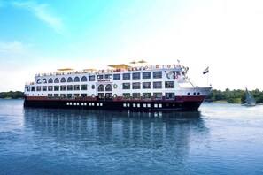 Un gran barco crucero fluvial de varias cubiertas y con una bandera.