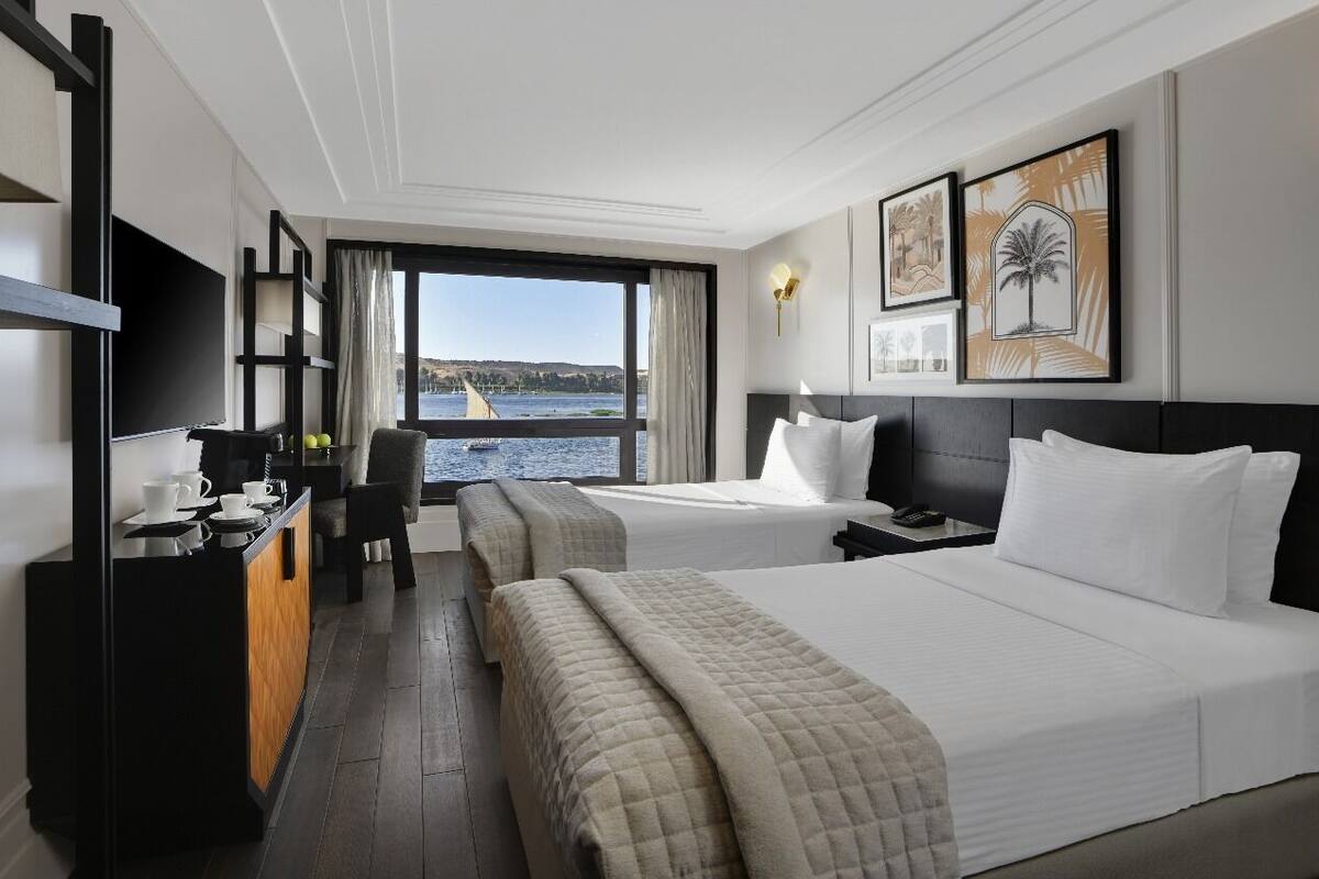 Une chambre d’hôtel avec deux lits, un bureau avec une télévision et une vue sur l’eau.