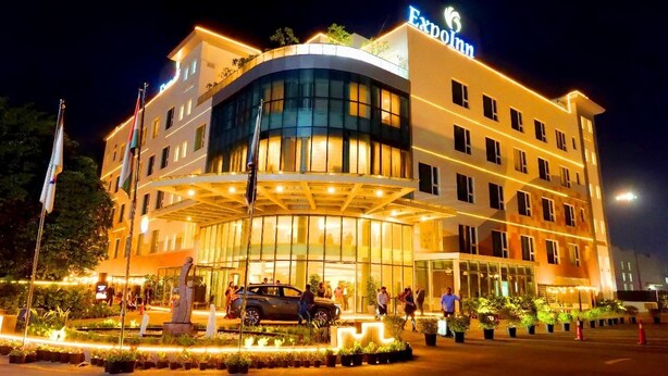 A hotel with a curved facade, multiple floors, and a well-lit entrance. - ExpoInn Suites and Convention (Greater Noida)