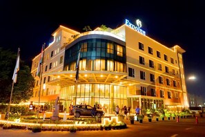 A hotel with a curved facade, multiple floors, and a well-lit entrance.
