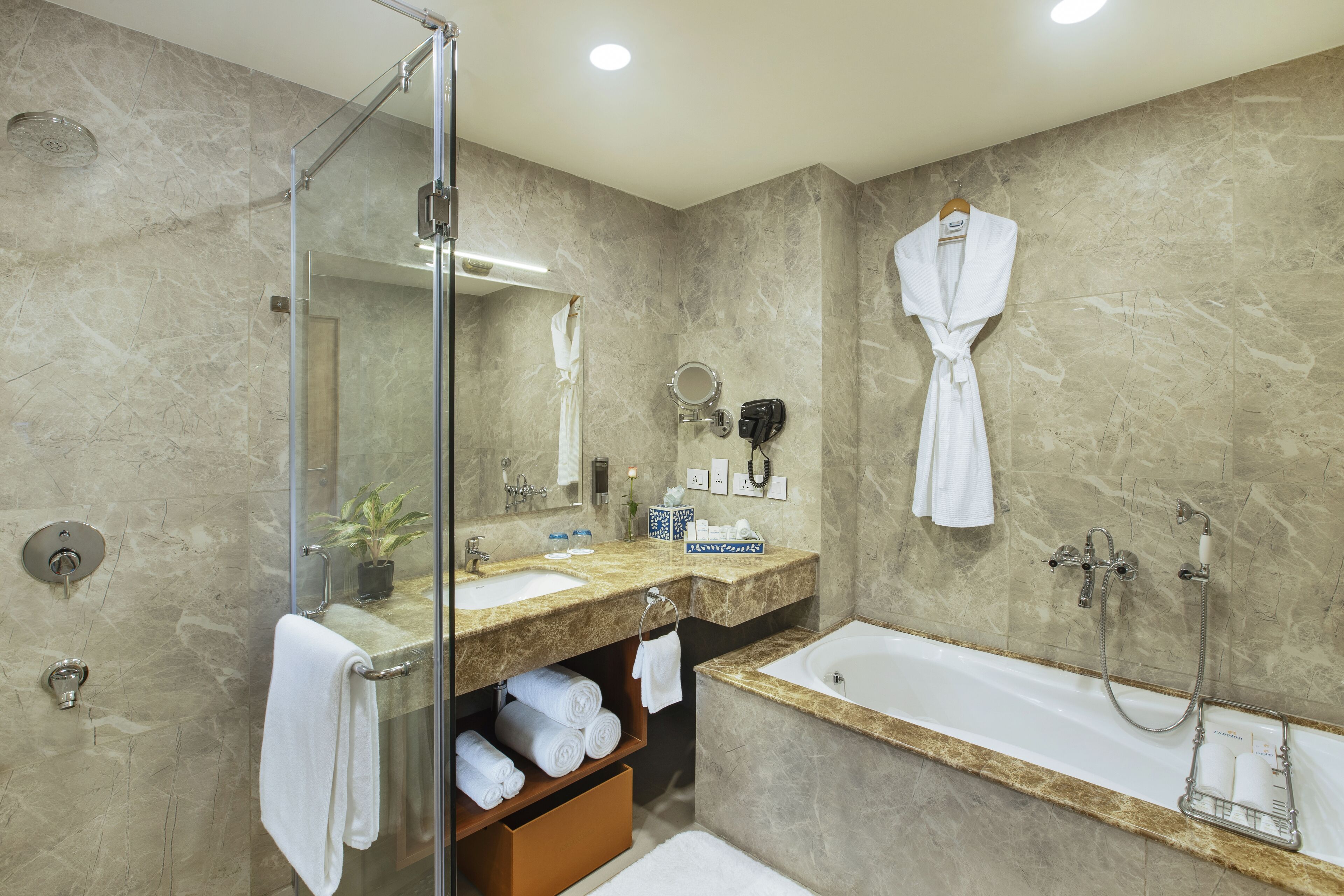 Ein modernes Badezimmer mit einer Duschkabine, einer großzügigen Badewanne und einem Waschtisch mit Spiegel und Handtuchhalter.