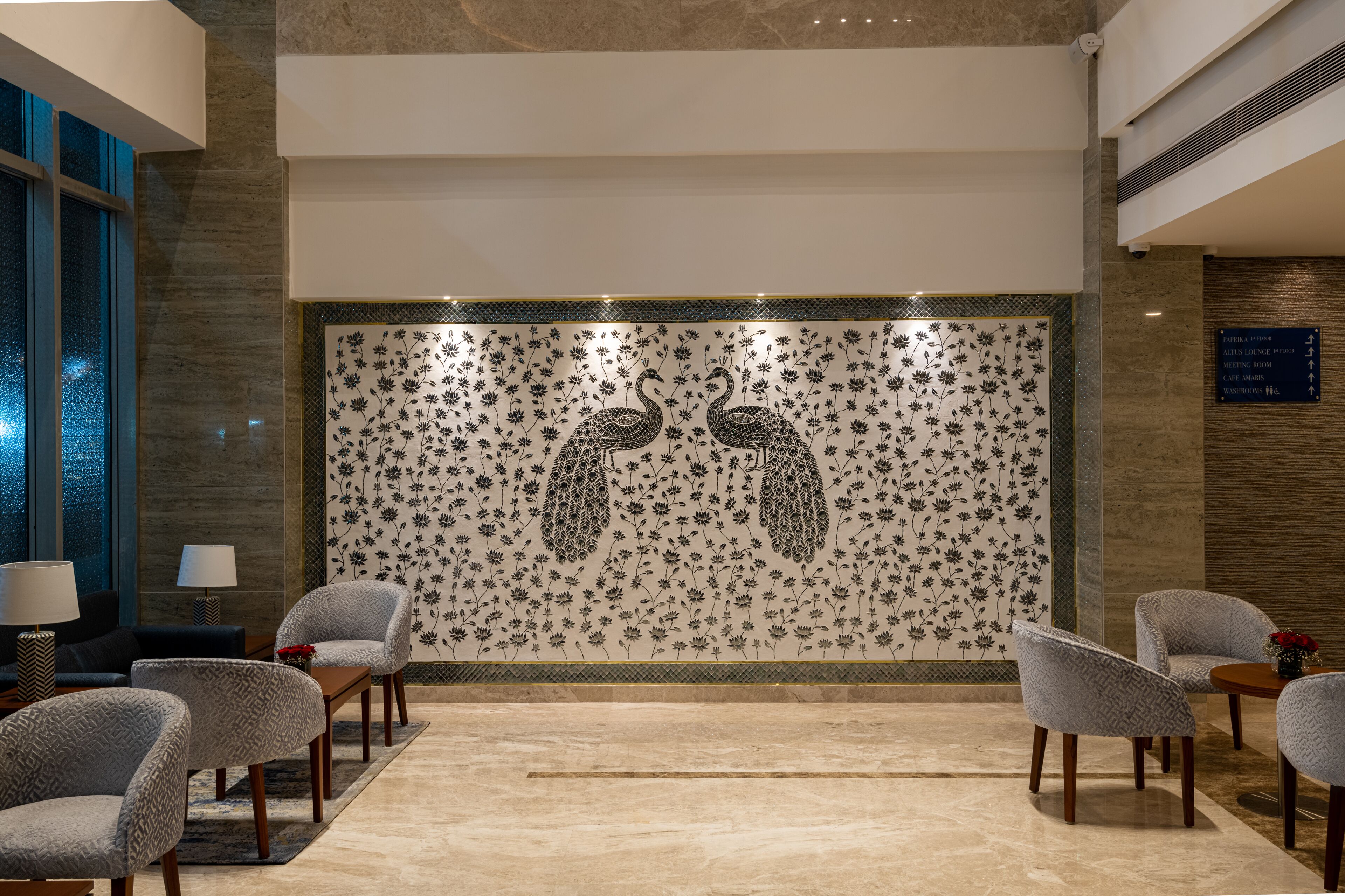 Una hall con un murale floreale, zona salotto e reception.