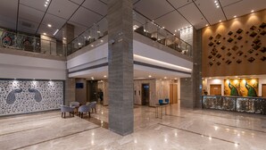 A spacious lobby with a marble floor, a reception desk, and a seating area with chairs. - ExpoInn Suites and Convention (Greater Noida)