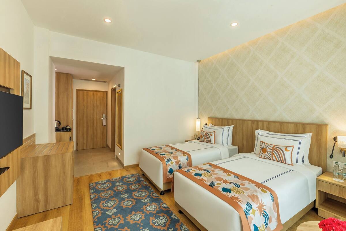 A hotel room with two beds, a TV, a desk, and a bathroom.