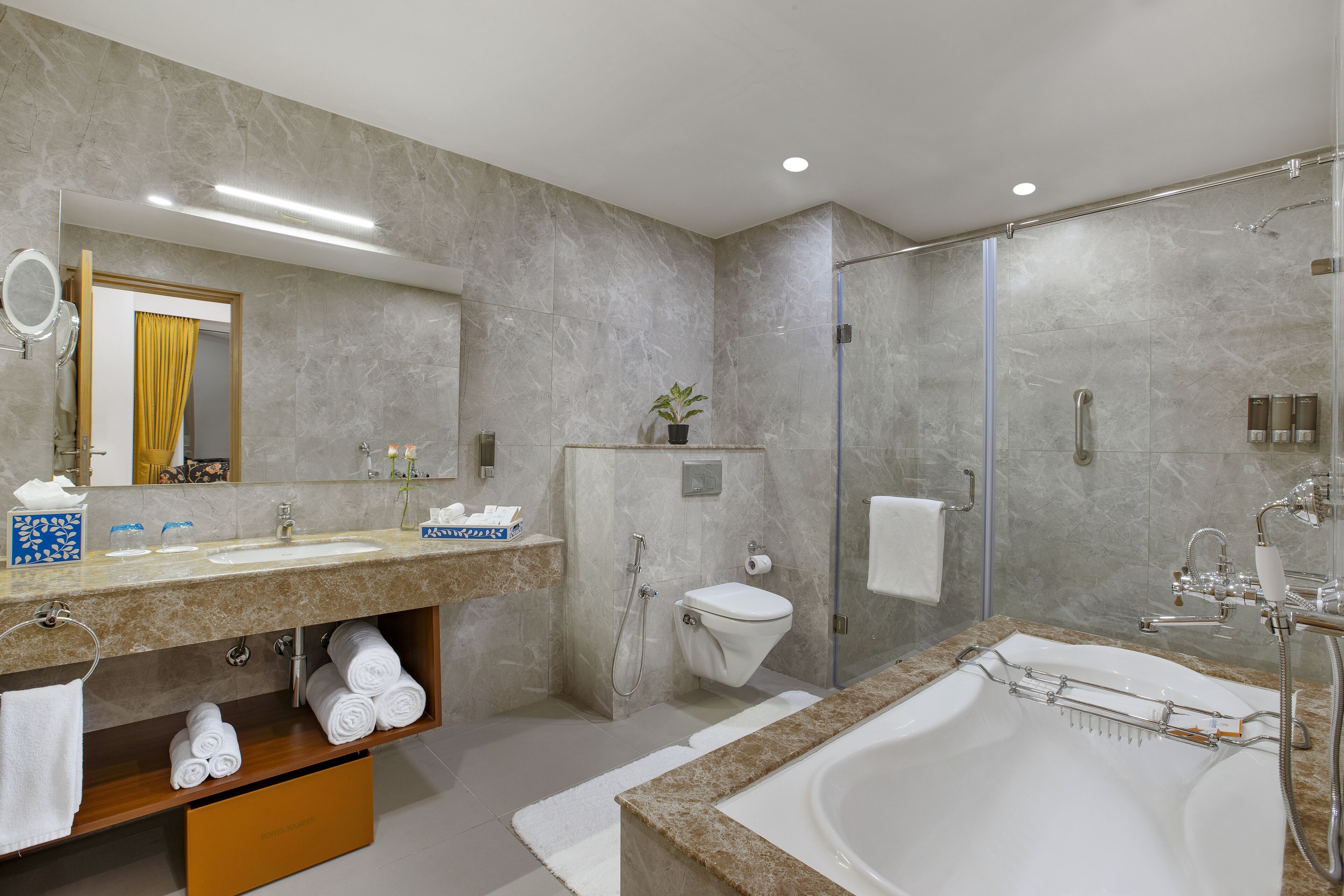 A modern bathroom with a large bathtub, a separate shower area, and a vanity with a mirror and towel rack.