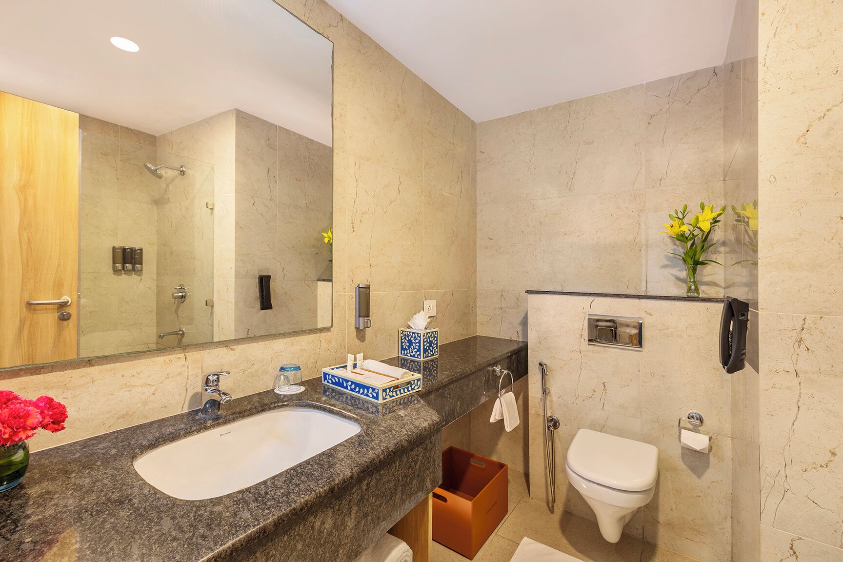 A bathroom with a double sink, a toilet, a shower, and a large mirror.