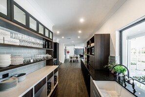 Una cocina moderna con armarios oscuros, una isla central y vistas al exterior.