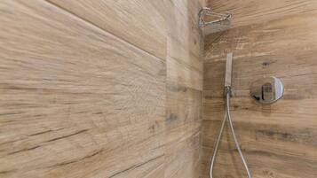 A wooden wall with a shower fixture and a towel rack.