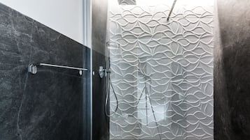 A modern shower with a textured wall and a metal handrail.