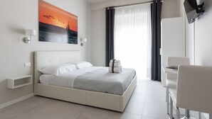 A modern hotel room with a large bed, a desk, and a TV mounted on the wall. - PhotoRooms B&B (Syracuse)