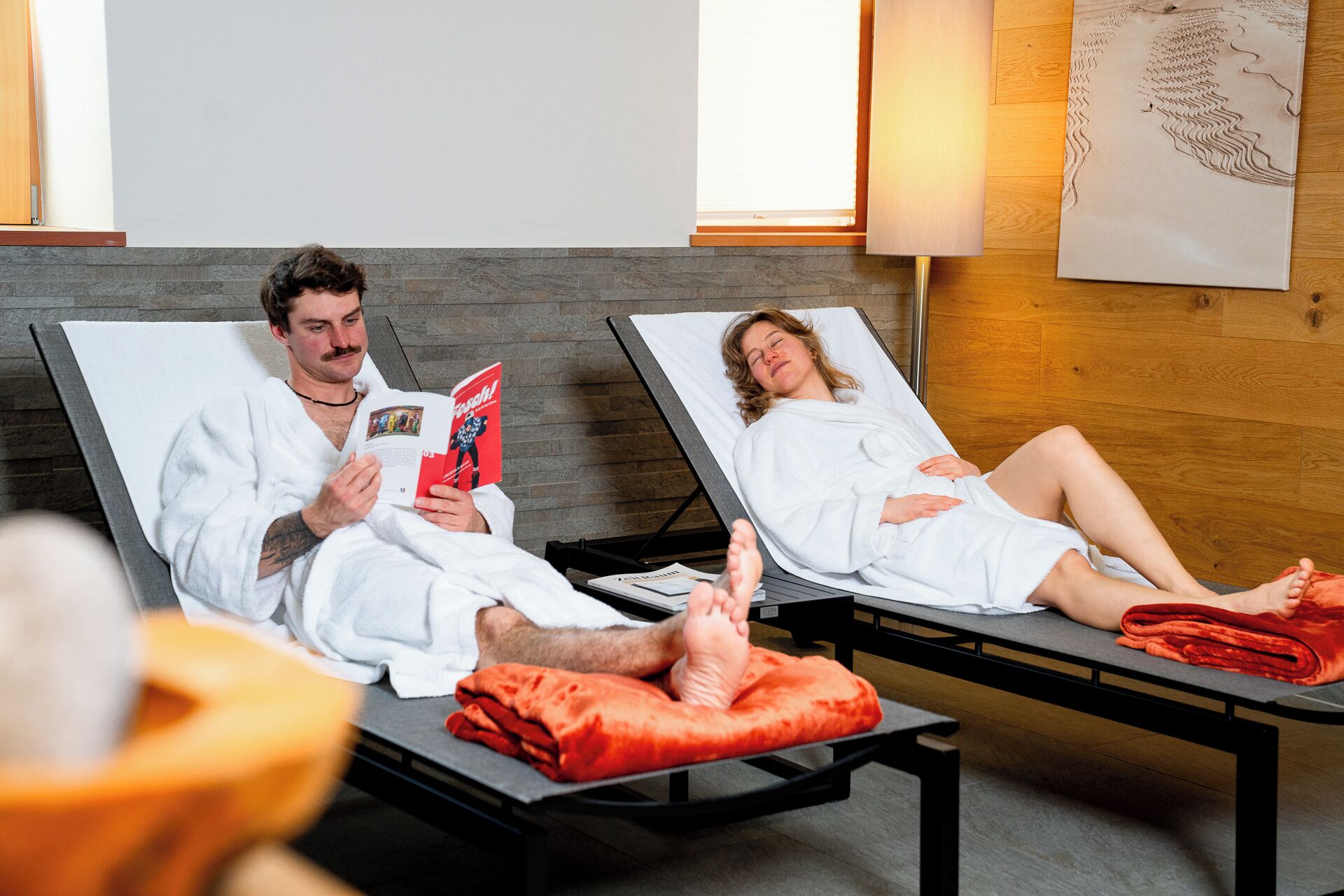 Two lounge chairs with white towels, a red blanket, and a magazine.