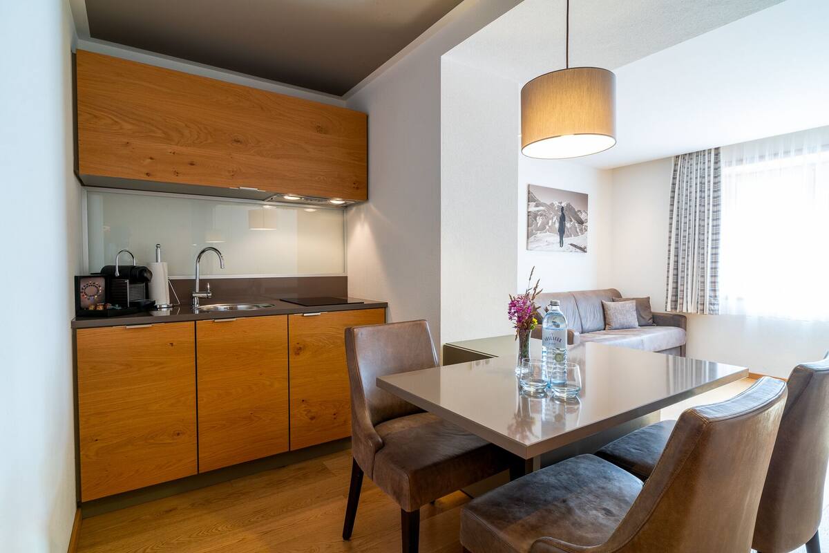 A modern kitchen with wooden cabinets, a built-in sink, and a dining area with a table and chairs.