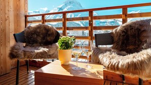 Two furry chairs with a wooden table, a yellow pot with green plants, and two wine glasses. - Apart-Hotel Laurus (Lech am Arlberg)