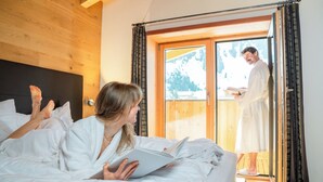 A bedroom with a bed, a wooden headboard, and a sliding glass door leading to an outdoor area. - Apart-Hotel Laurus (Lech am Arlberg)