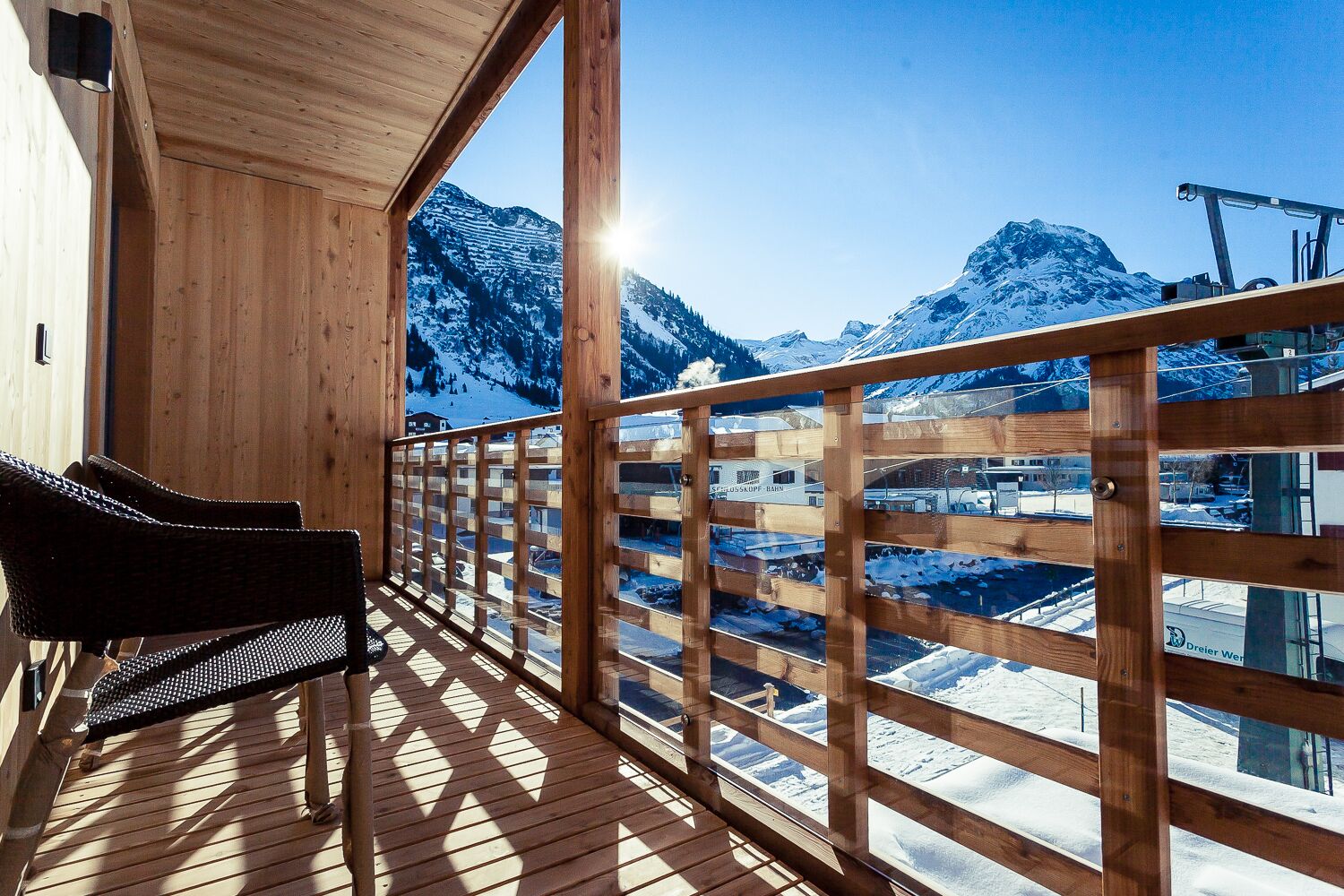 A wooden deck with a bench, wooden railing, and a view of snow-covered mountains.