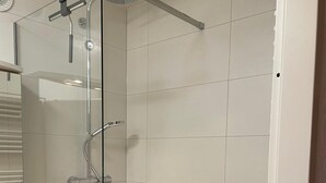 A modern shower with glass doors, a handheld showerhead, and a wall-mounted faucet. - Apartment Thermen-zeit (Bad Fuessing)