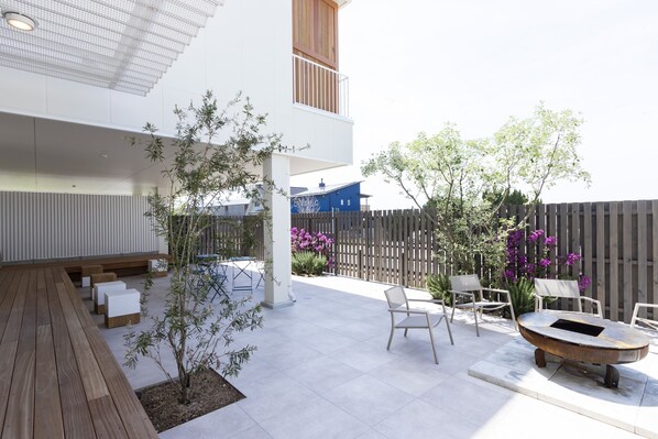 Un patio moderno al aire libre con piso de madera, zona de estar y una mesa metálica original.
