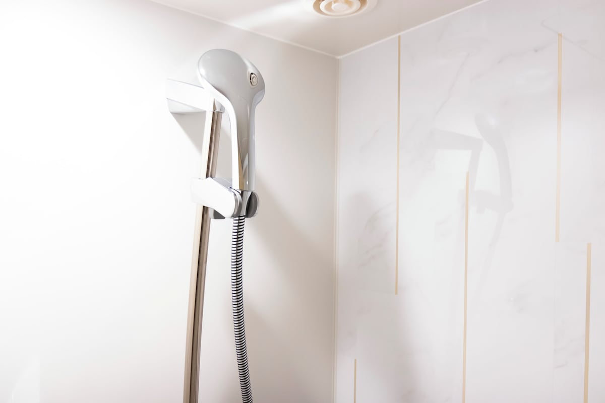 A shower with a handheld attachment and a flexible hose.