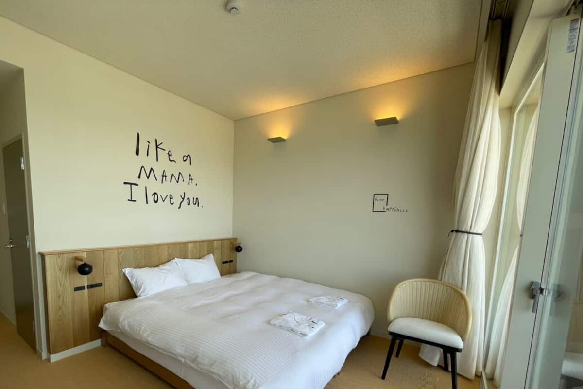 Una habitación de hotel con una cama grande, una silla, una pared con un mensaje y una puerta.