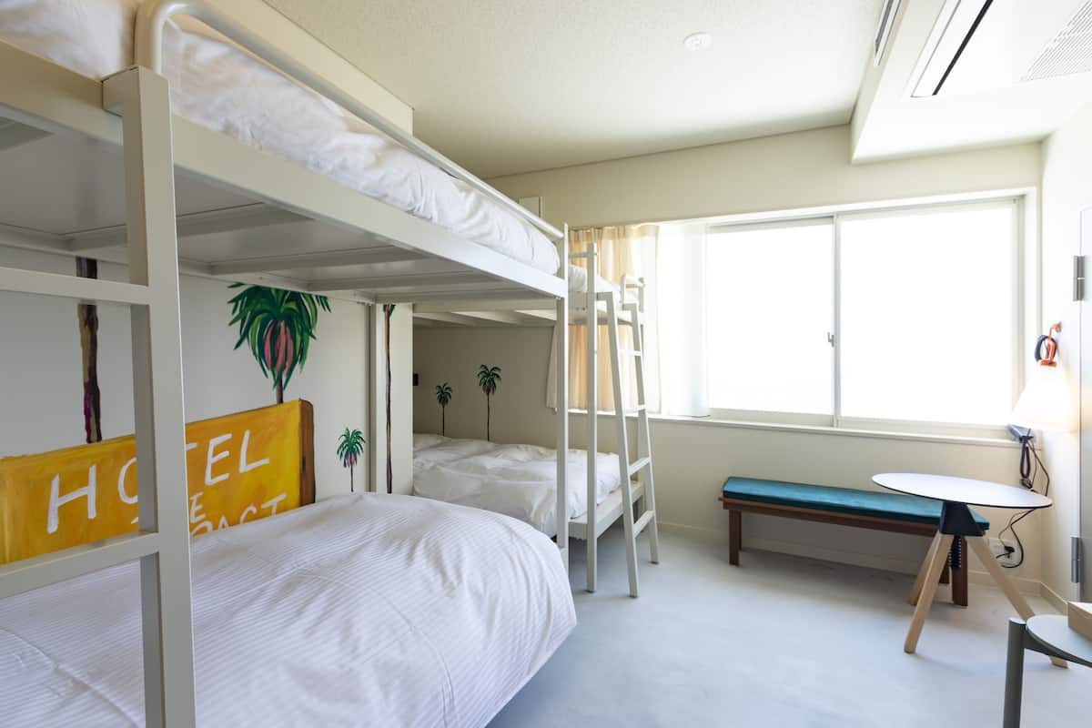 Una habitación de hotel con literas, un escritorio y un banco.