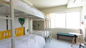 A hotel room with bunk beds, a desk, and a bench.