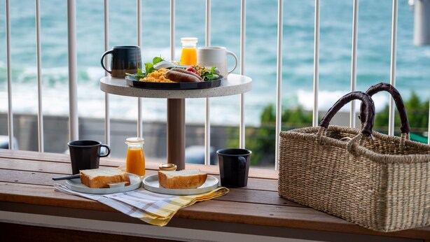 A breakfast setup on a balcony with a view of the sea, including toast, eggs, and juice. - KAMOME SLOW HOTEL THE COMPACT (Awaji)