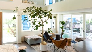 A modern living space with a large tree, seating area, and a staircase leading to an upper level. - KAMOME SLOW HOTEL THE COMPACT (Awaji)